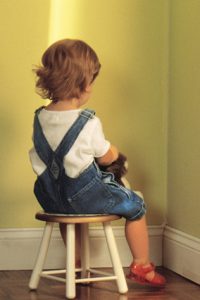 Young child sitting in corner as punishment